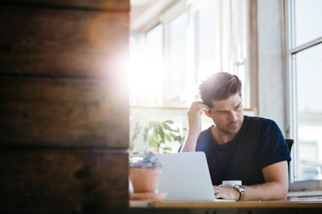 photo of a man looking away from laptop with a worried expression