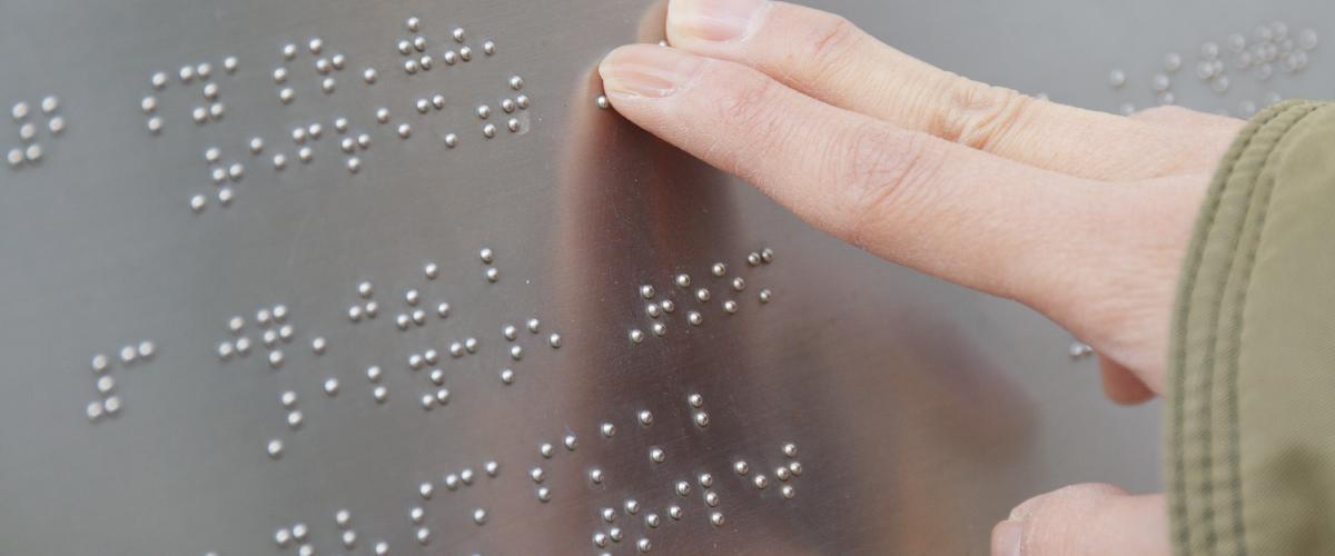 photo of a person's fingers reading a braille directory.