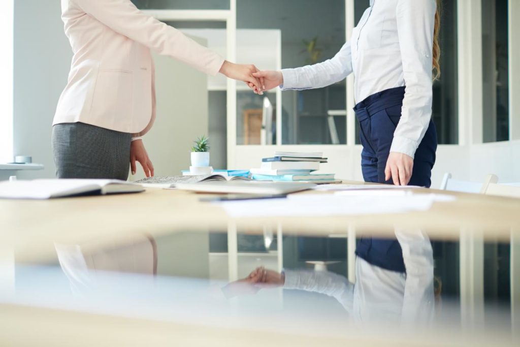 photo of two business women in an office shaking hands