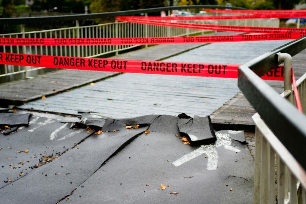 photo of broken asphalt with "danger keep out" tape blocking entrance.
