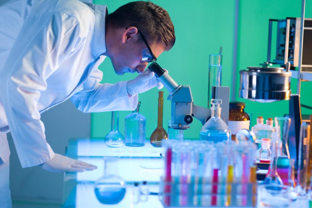 Side view of male scientist analyzing something through a microscope in a laboratory