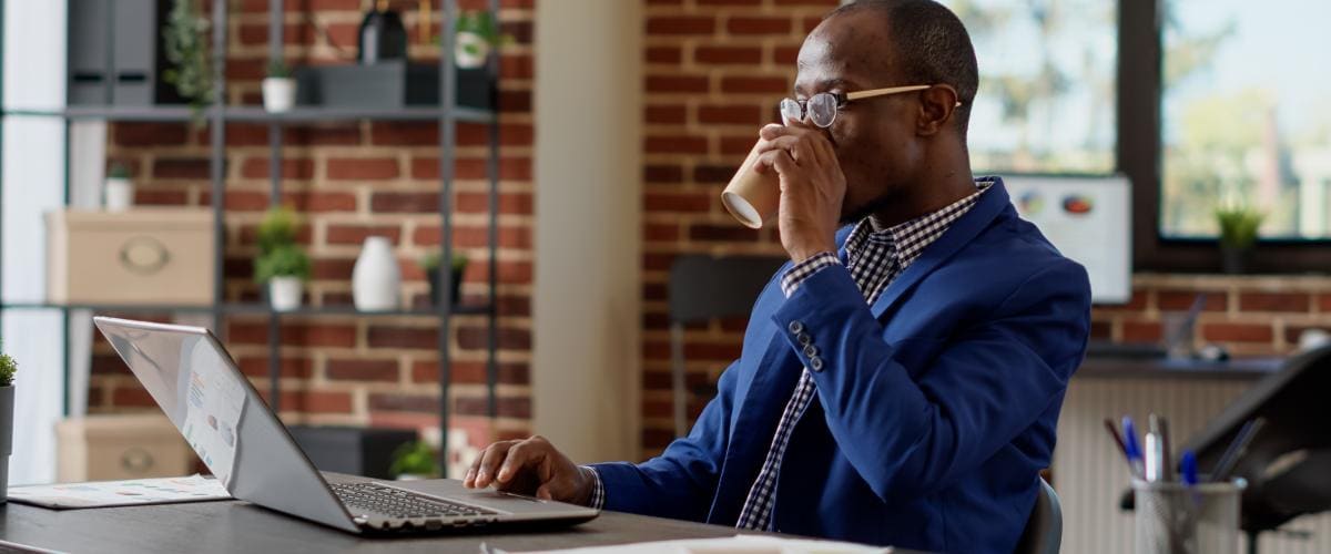worker on laptop drinking coffee in an office