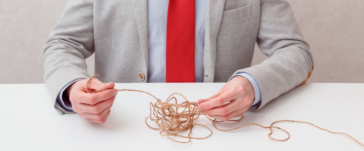 body and hands of a person trying to untangle a piece of twine.