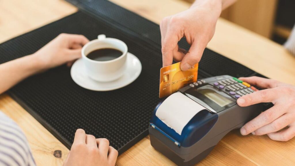 Close up of transaction with credit card in cafe for coffee.