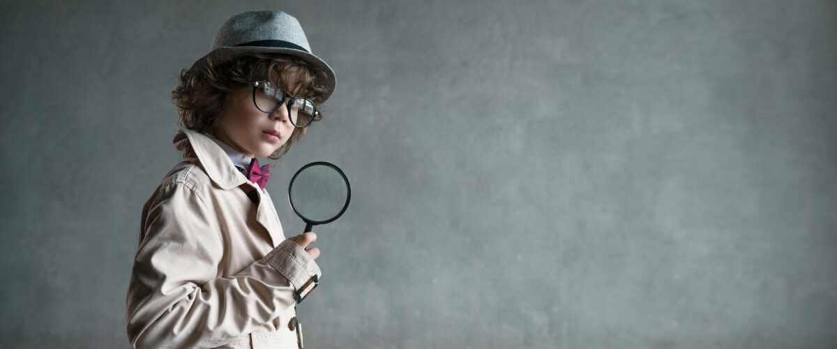 Child dressed up like Sherlock Holmes, a fictional detective, with a gray background